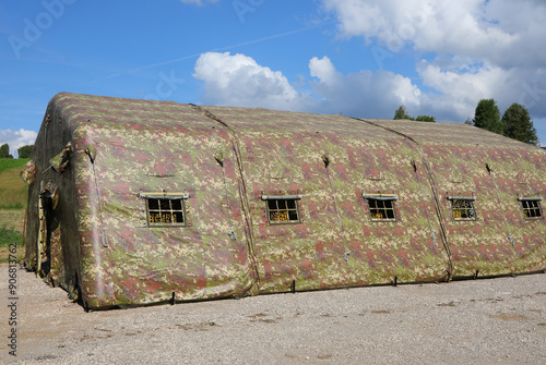 camouflaged military tent set up in a camp during wartime with no people visible