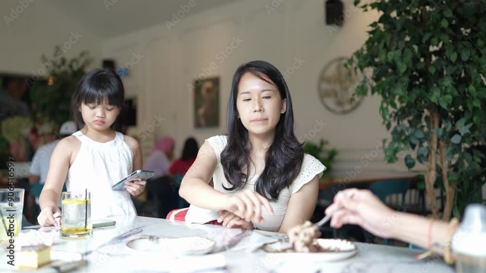 Slow-motion video of 20-something Chinese Malaysian woman in white clothes and 7-year-old girl in white dress having conversation at table in stylish café in Selangor, Malaysia. Slow-motion video of 20-something Chinese Malaysian woman in white clothes and 7-year-old girl in white dress having conversation at table in stylish café in Selangor, Malaysia.
