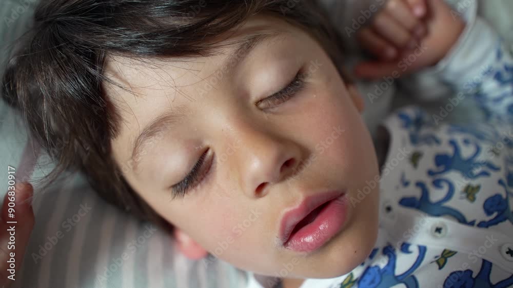 Young boy sleeping with head on pillow, mouth open slightly, highlighting tranquility and peacefulness in a close-up