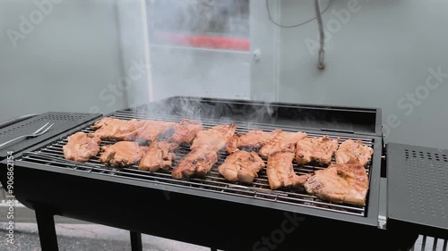 Sizzling Pork Grilling in a Garage: A Tasty BBQ with Fragrant Smoke, Charred Perfection, and Delicious Flavors for a Savory Outdoor Cooking Experience.