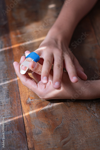 Close-up of the hands of an unrecognizable young boy applying a corrective splint to the little finger of his right hand. Copy space in vertical composition. photo