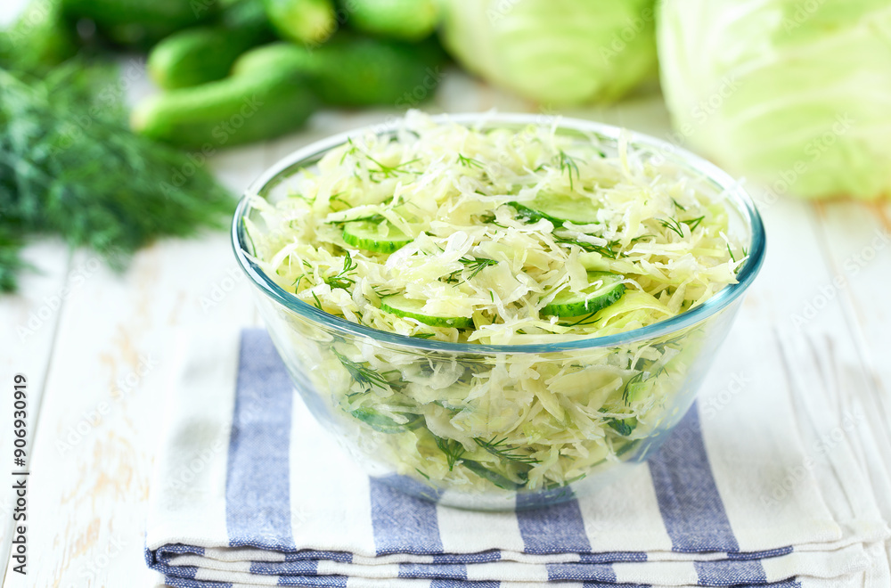 Bowl of spring vegan salad with cabbage, cucumber and dill on a white kitchen table, selective focus.Vegetarian salad. Bowl of spring vegan salad with cabbage, cucumber and dill on a white kitchen table, selective focus.Vegetarian salad.