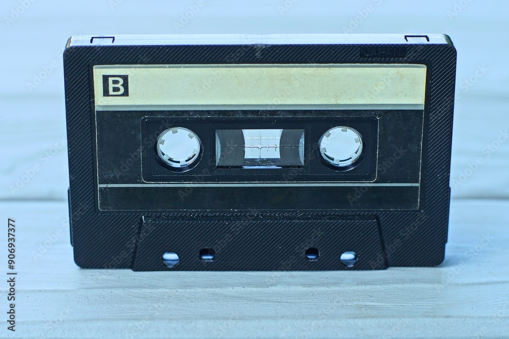 Obraz premium one old black retro magnetic tape and music recording in plastic transparent box audio cassette stands on gray wooden table