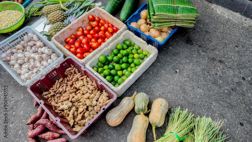 A vibrant display of fresh produce including tomatoes, ginger, and lime at an Asian street market, symbolizing local agriculture photo