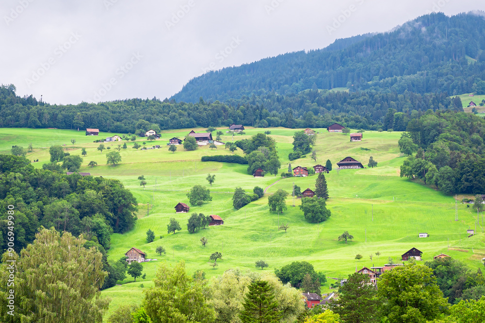 Obraz premium Beautiful view of little houses and wooden cottages on a green mountain meadow near the village of Sarnen in central Switzerland