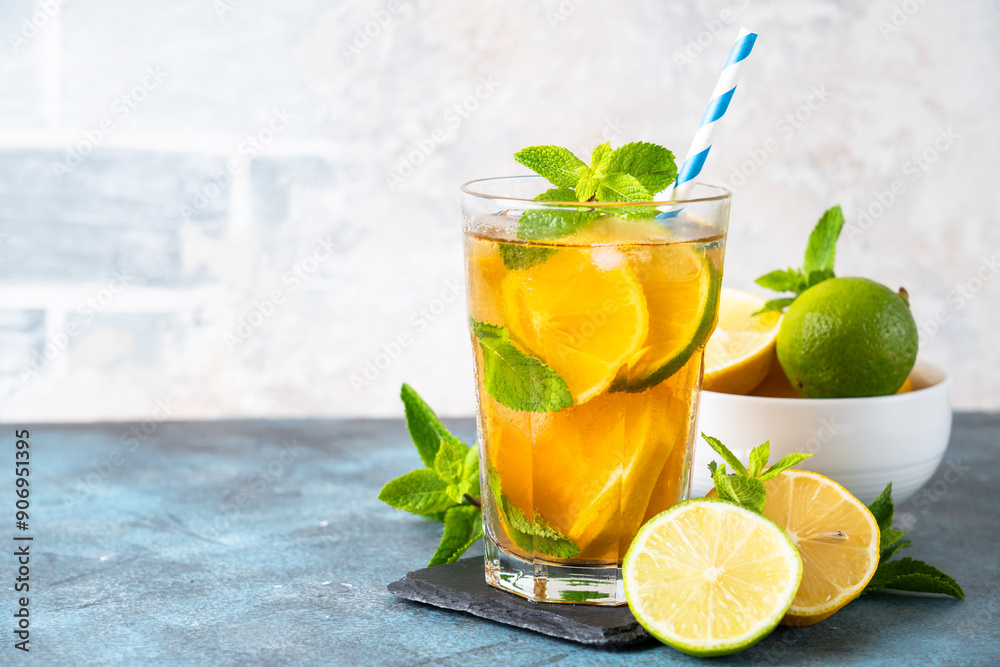 Fototapeta premium Iced tea with ingredients. Black tea with lemon, lime, mint and ice. Cold lemonade, summer drink at kitchen table.