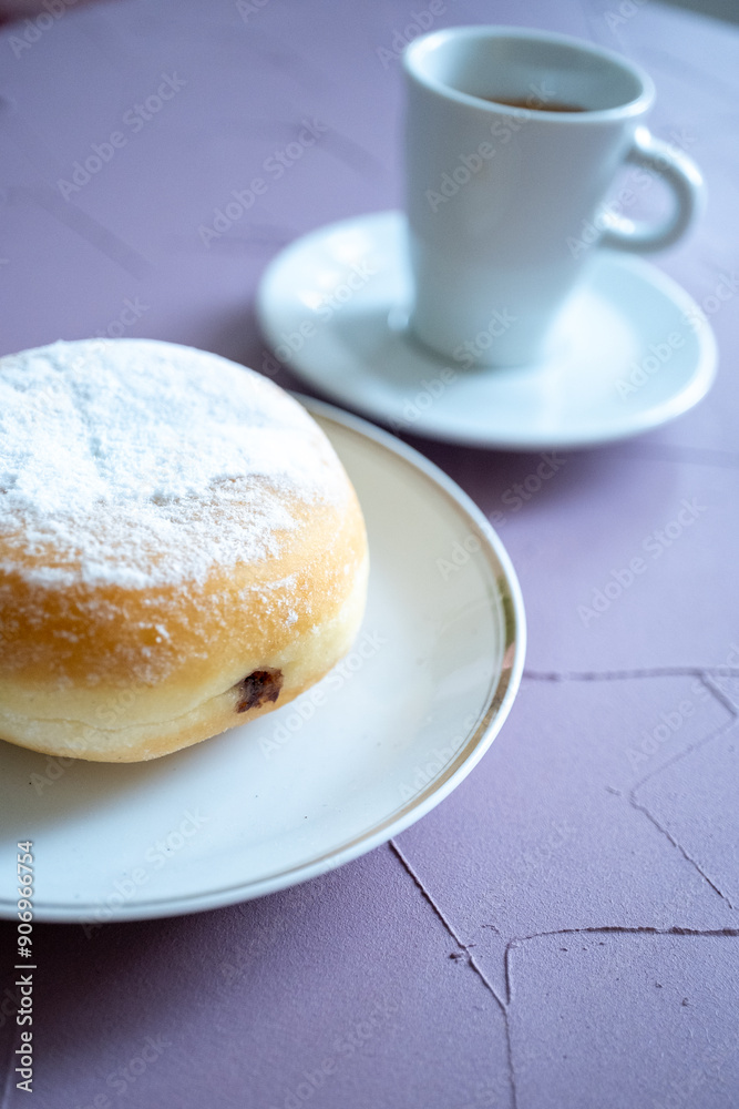 Close-up of berliner cake on a white plate and a cup of espresso