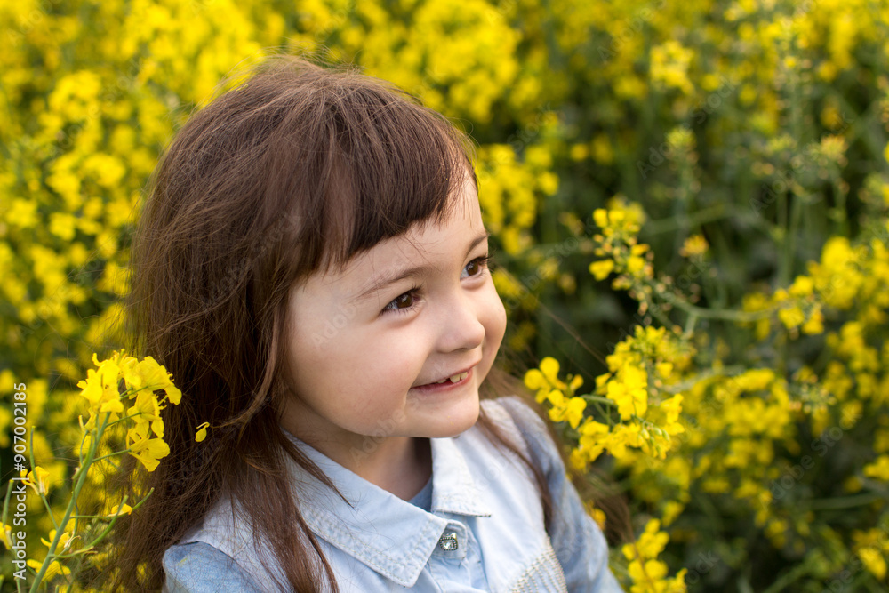 little girl in a field of blooming yellow flowers. girl with yellow rapeseed flowers