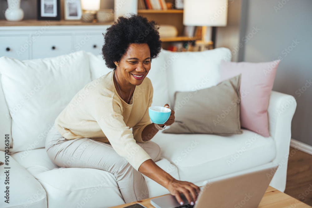 Smiling young black woman in knitted sweater freelancer working from home, sitting on couch, using laptop, copy space. Relaxed african american lady enjoying her weekend, surfing on internet on laptop Smiling young black woman in knitted sweater freelancer working from home, sitting on couch, using laptop, copy space. Relaxed african american lady enjoying her weekend, surfing on internet on laptop