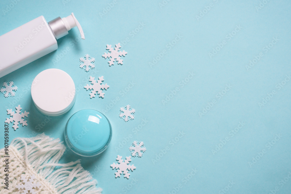 Winter cosmetic with knitting scarf on blue background. Flat lay with copy space. Winter cosmetic with knitting scarf on blue background. Flat lay with copy space.