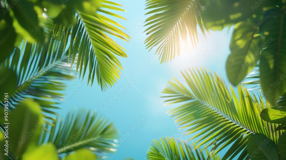 Naklejka premium Upward view of lush palm leaves against a bright blue sky, capturing the essence of tropical nature and sunlight.