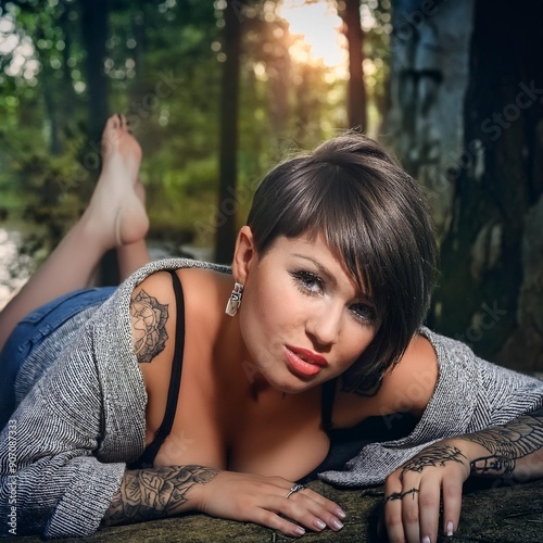 portrait of a woman lying in the grass, tattoos