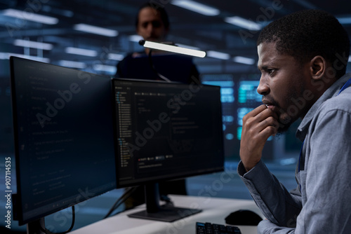 African american technician frowning after seeing error in server hub while overseeing supercomputers used for managing databases. Employee in data center feeling stressed after noticing malfunction photo