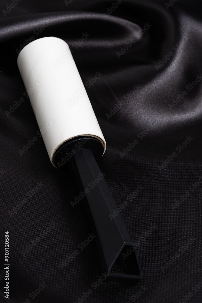 Fototapeta premium Roller for cleaning clothes on background black satin fabric.