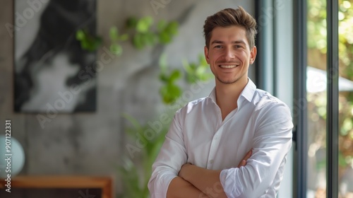 Smiling young businessman in a white shirt stands confidently with arms crossed in modern office environment, conveying sense of success and professionalism in his workplace., banner with copy space