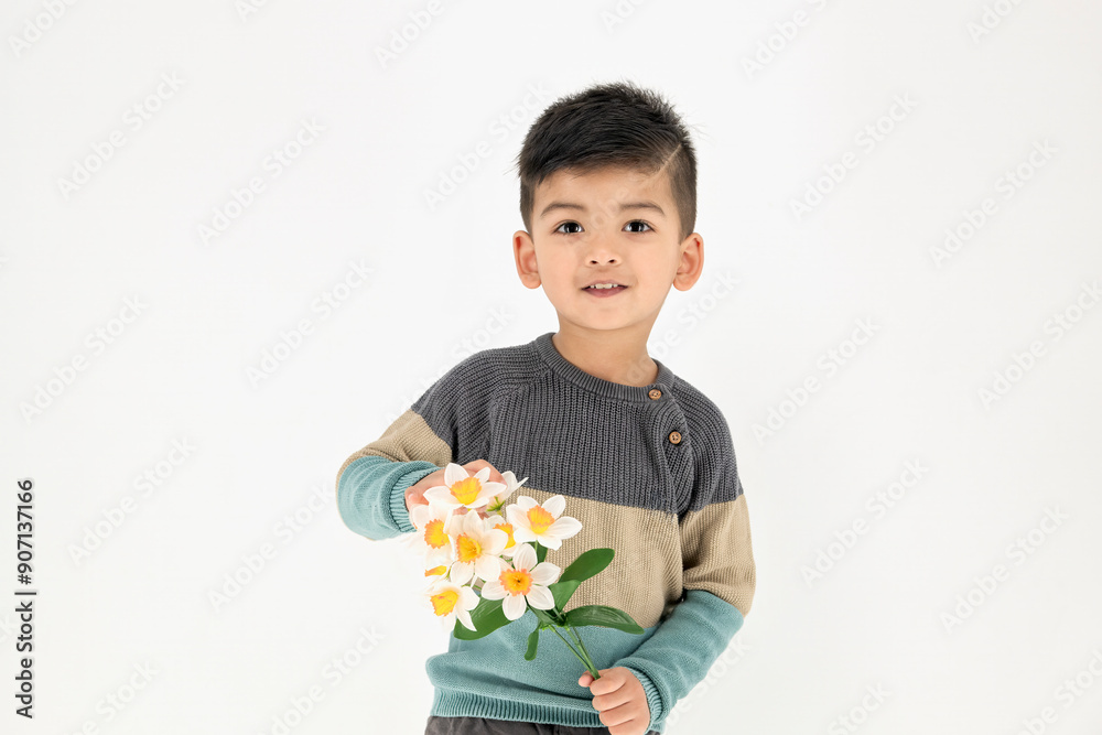 Cute positive child boy looks at the camera holding bunch of flowers on a white background. Mom's Day, exhibits joy and innocence. Banner with copy space... Cute positive child boy looks at the camera holding bunch of flowers on a white background. Mom's Day, exhibits joy and innocence. Banner with copy space...