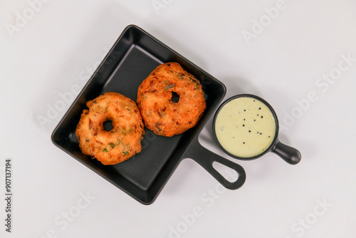 Medhu Vadai is a traditional South Indian delicacy known for its exquisite taste and crispy texture. Vadai, medu vada, uzhunnu Vada, black lentil fritters with coconut chutney on plate served hot.  photo