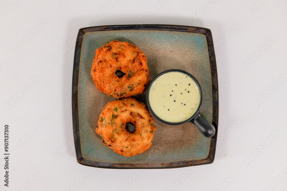 Medhu Vadai is a traditional South Indian delicacy known for its exquisite taste and crispy texture. Vadai, medu vada, uzhunnu Vada, with coconut chutney on plate served hot.