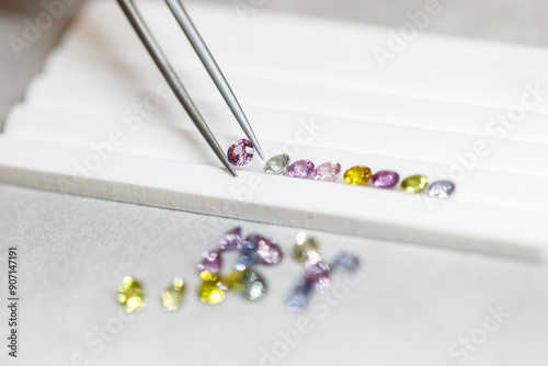multi-colored sapphires. Gems. A jeweler selects precious stones using a tool. View from above. Macro photography.