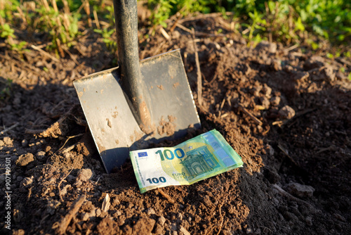 Shovel with Euro money on ground. Bury money. Digging money in soil. Digs EURO coins note from ground. EURO bills in European Union Crisis. Euro bills growing out of soil. Burying money in backyard.