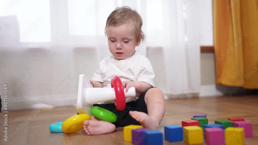 a small child is playing. happy childhood dream concept for a little child. cute little child in a white t-shirt plays with different colorful toys while sitting on the lifestyle floor a small child is playing. happy childhood dream concept for a little child. cute little child in a white t-shirt plays with different colorful toys while sitting on the lifestyle floor