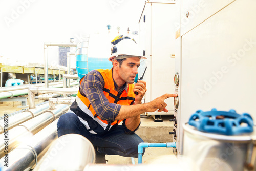 HAVC refrigeration system mechanic daily inspection refrigeration equipment on the roof building checking pressure and electrical control systems using radio communications to report technician team.