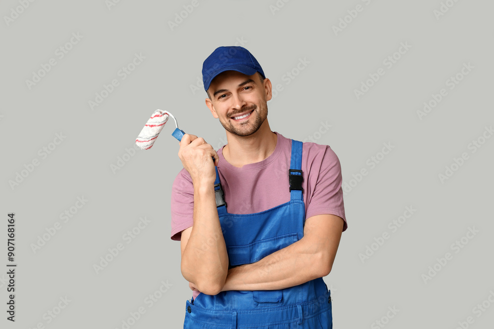 Portrait of male painter with paint roller on grey background Portrait of male painter with paint roller on grey background