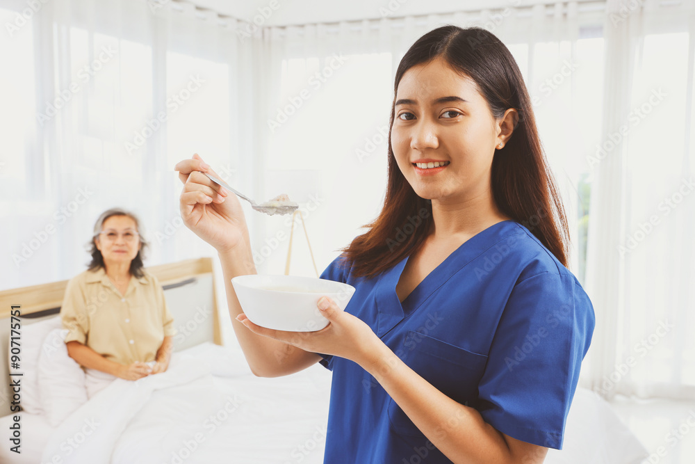 Portrait cute female nurse takes care elderly patient sitting on a bed standing holding nutritious easily digestible breakfast porridge that nourished her body to help her recover from her illness. Portrait cute female nurse takes care elderly patient sitting on a bed standing holding nutritious easily digestible breakfast porridge that nourished her body to help her recover from her illness.