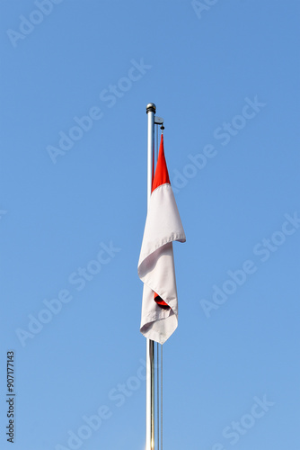 An Indonesian flag on the flag pole against clear blue sky background