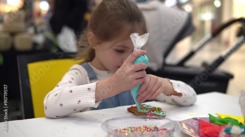 A joyful child is decorating cookies with colorful photo