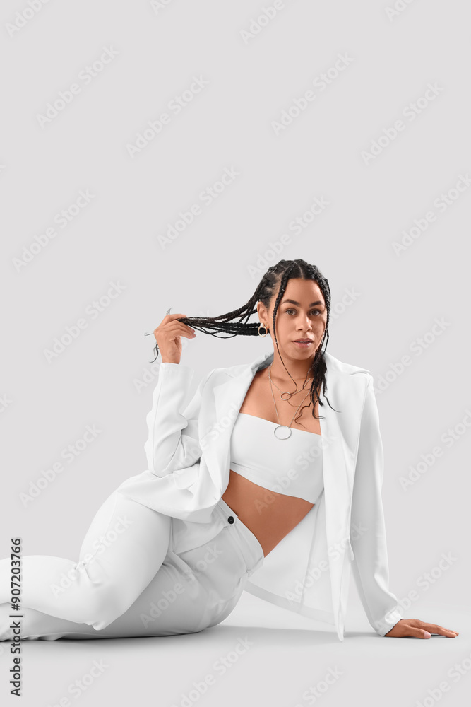 Stylish African-American woman with dreadlocks sitting on light background Stylish African-American woman with dreadlocks sitting on light background