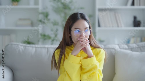 Young Asian woman with feeling sad and stressed, sick and headache, sitting on sofa in living room at home