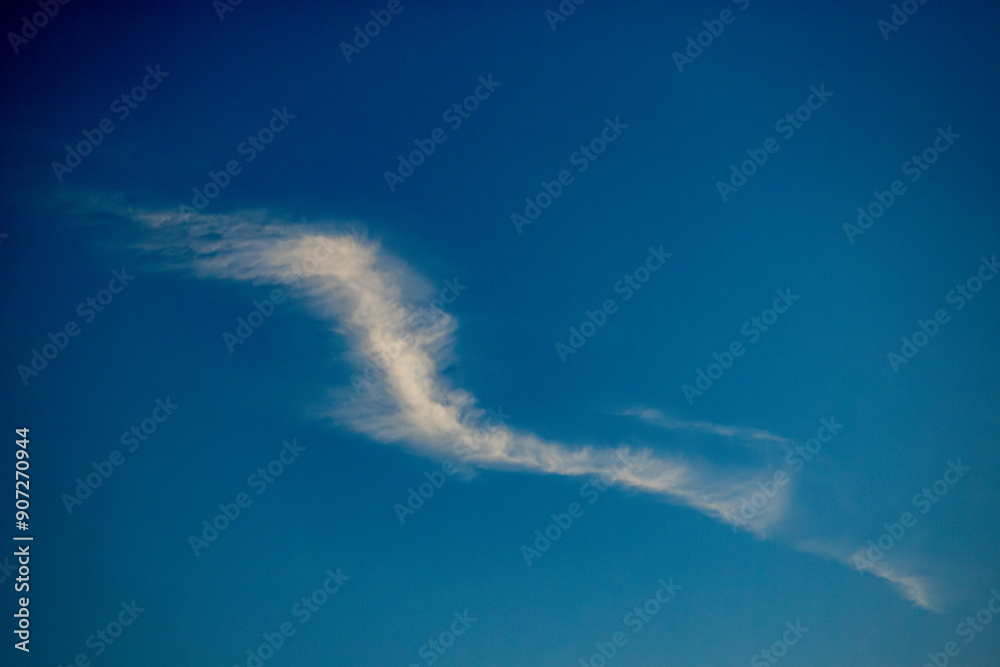 A thin, wispy cloud stretches across a clear blue sky, creating a serene and peaceful scene with ample copy space. A thin, wispy cloud stretches across a clear blue sky, creating a serene and peaceful scene with ample copy space.