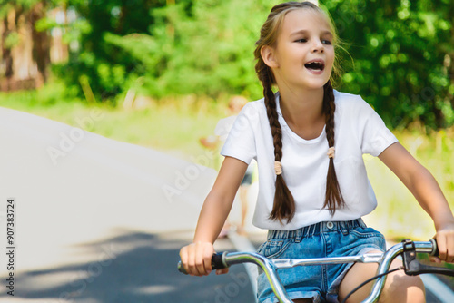 Child riding bicycle. Little kid girl on bicycle along bikeway. Happy cute little girl riding bicycle. Child cycling on bicycle.