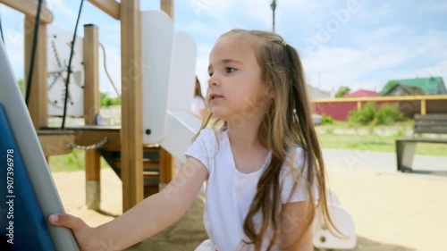 4k footage of funny toddler girl climbing on wooden stapladder on children playground at park photo