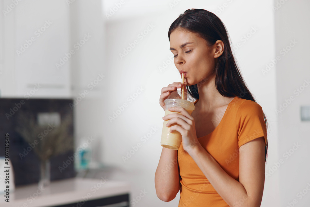Woman enjoying a healthy fruit smoothie in modern kitchen setting with white counter Woman enjoying a healthy fruit smoothie in modern kitchen setting with white counter