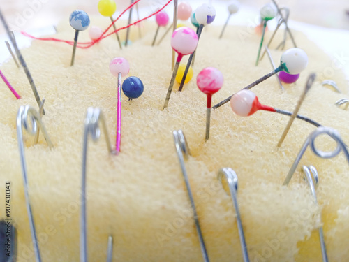 various types of needles in the yellow pin cushion. clothing sewing needle and thread. life hacks for pincushion. straight pin. pin. Close up