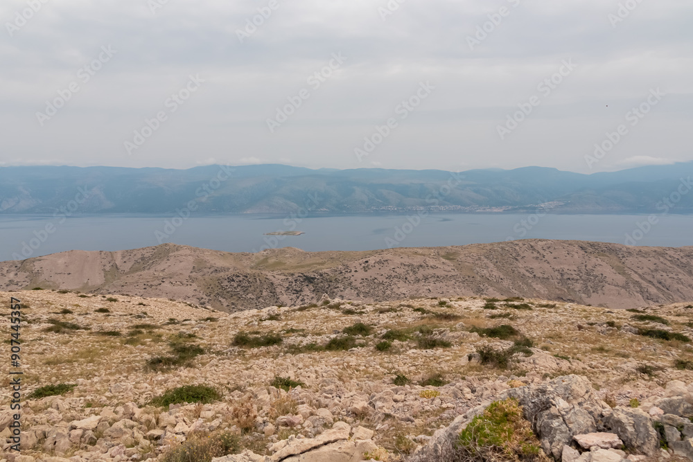 Scenic hiking trail on Moon Plateau in Baska, Krk Otok, Primorje-Gorski Kotar, Croatia. Rugged terrain with in sparse vegetation. Aerial view of Adriatic Sea on overcast day. Mediterranean landscape Scenic hiking trail on Moon Plateau in Baska, Krk Otok, Primorje-Gorski Kotar, Croatia. Rugged terrain with in sparse vegetation. Aerial view of Adriatic Sea on overcast day. Mediterranean landscape
