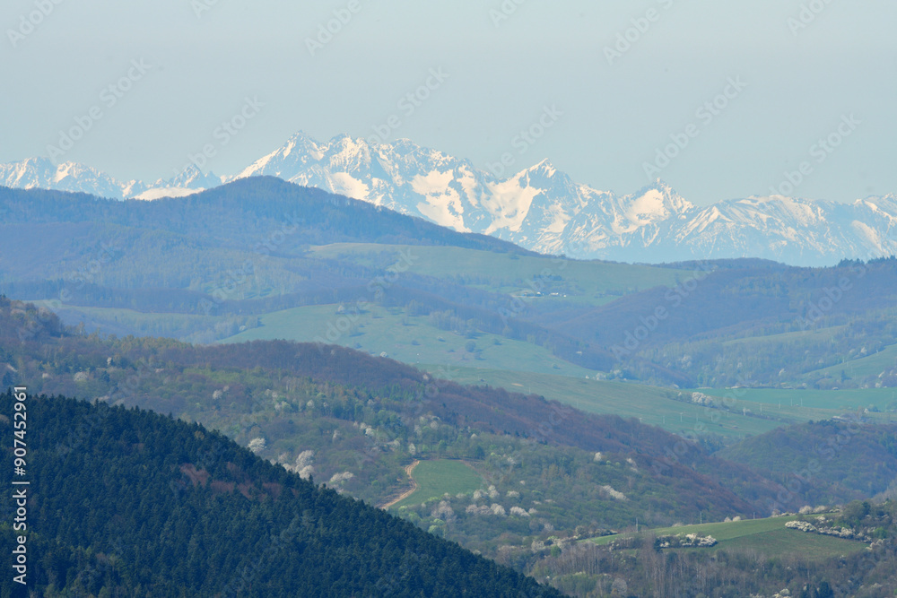 A distant view from the hill of the high peaks of snow-capped mountains High Tatra in spring