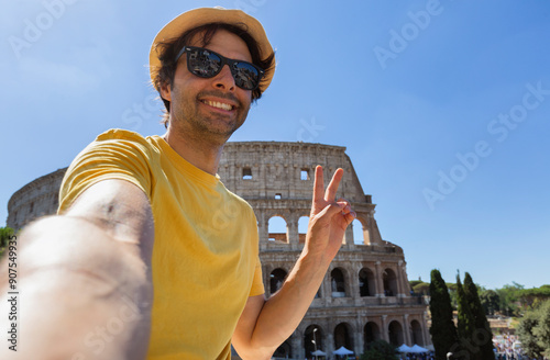 Canvas Print Happy young man making selfie and V sign in front of Colosseum in Rome, Italy
