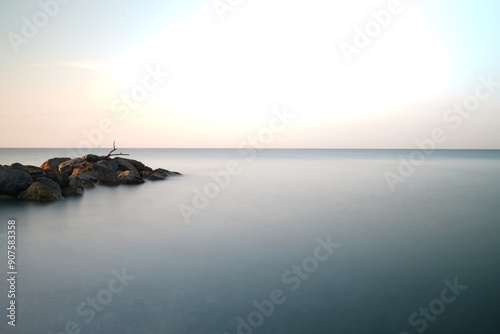 Alba poetica al mare con uno scoglio a sinistra in lunga esposizione che tutto appaia come in un sogno che porta alla pace interiore ed all'amore universale