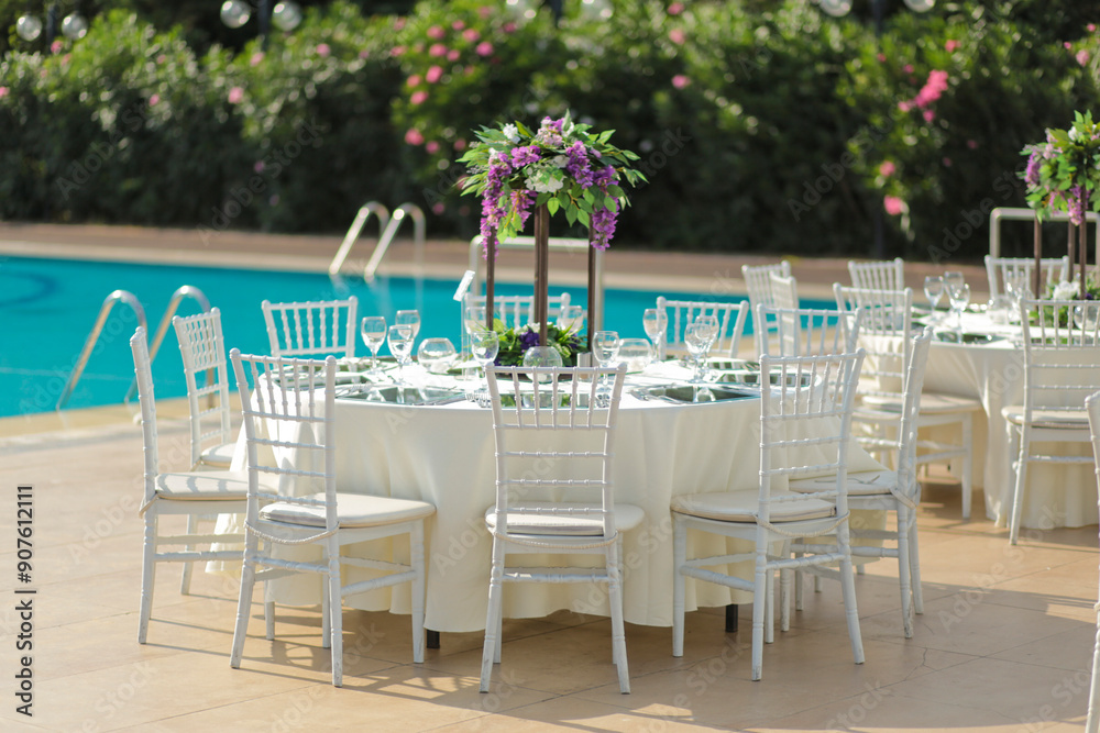 Elegant Outdoor Table Setting by the Pool with Colorful Floral Centerpieces Elegant Outdoor Table Setting by the Pool with Colorful Floral Centerpieces