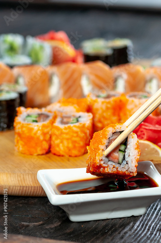 sushi set different types on a wooden board with sushi on sticks in soy sauce