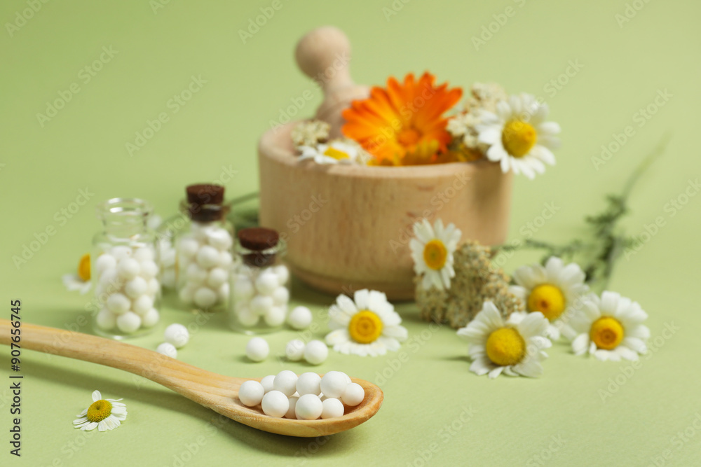 Homeopathic remedy, mortar and flowers on light green background, selective focus Homeopathic remedy, mortar and flowers on light green background, selective focus