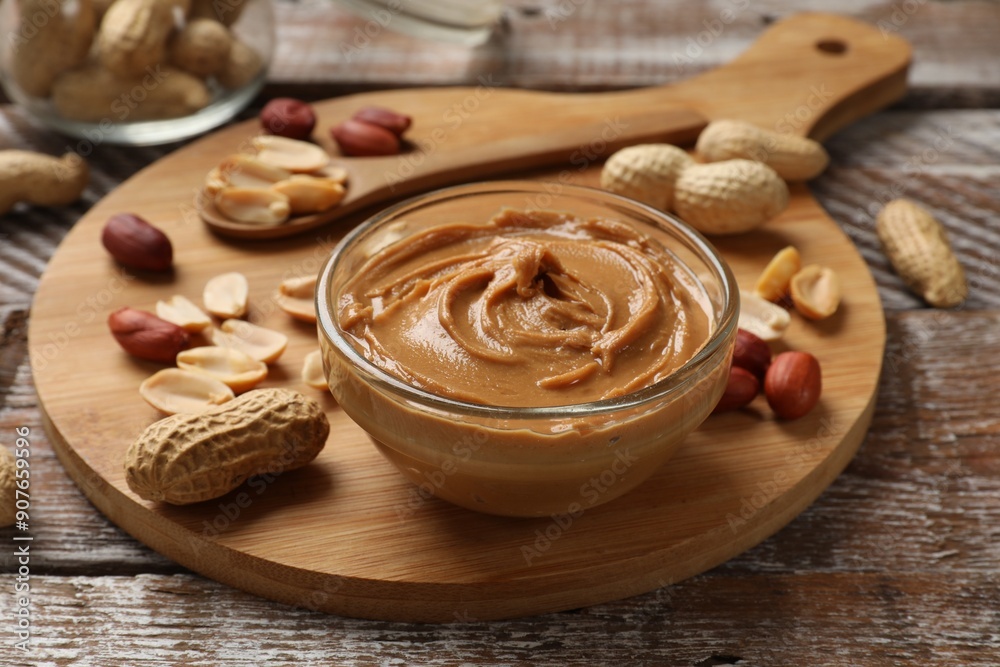 Tasty peanut butter in bowl and groundnuts on wooden table Tasty peanut butter in bowl and groundnuts on wooden table