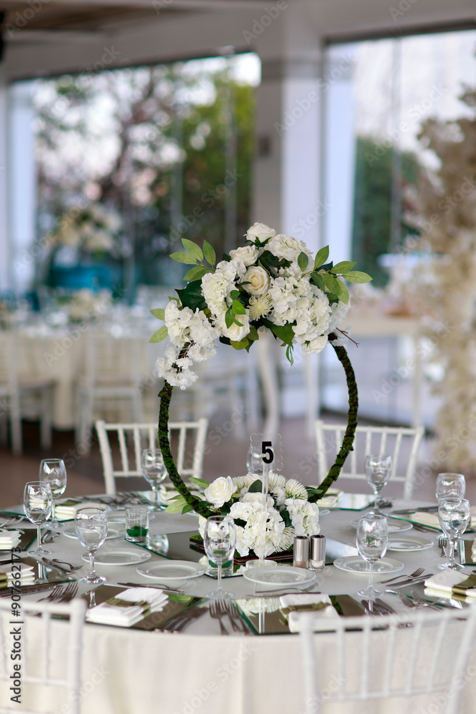 Indoor Wedding Setup: Round Tables and Floral Decor in White and Green