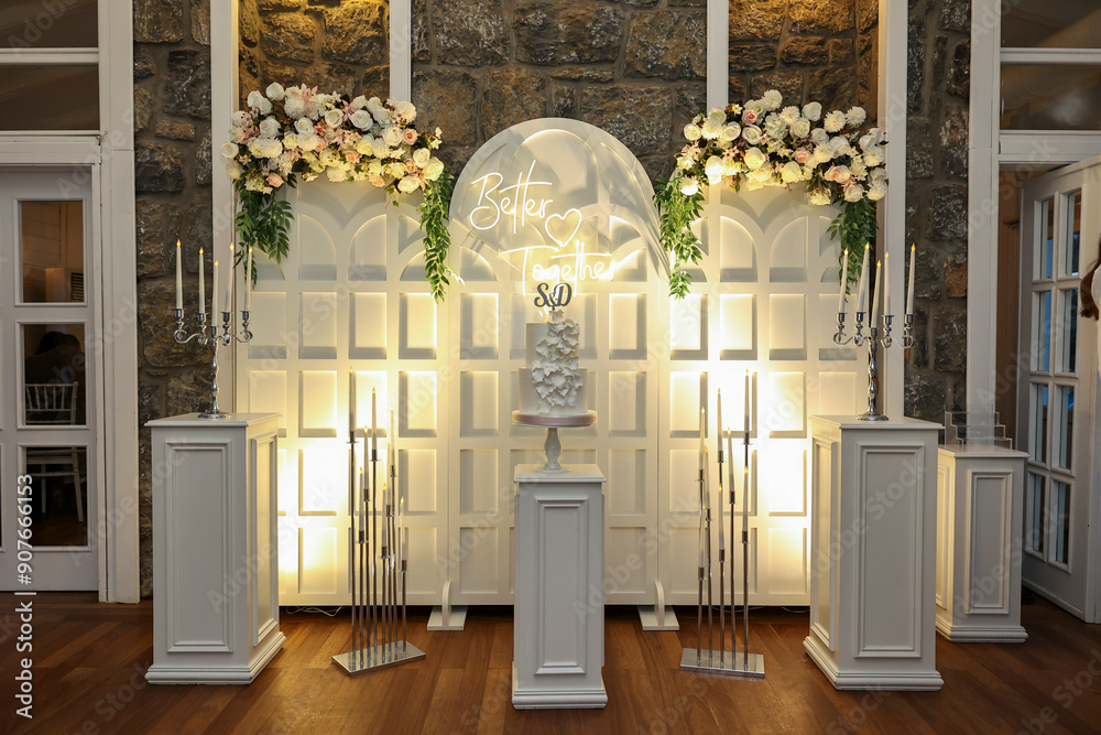Refined Wedding Cake Presentation with Flowers and Lighting Inside Venue