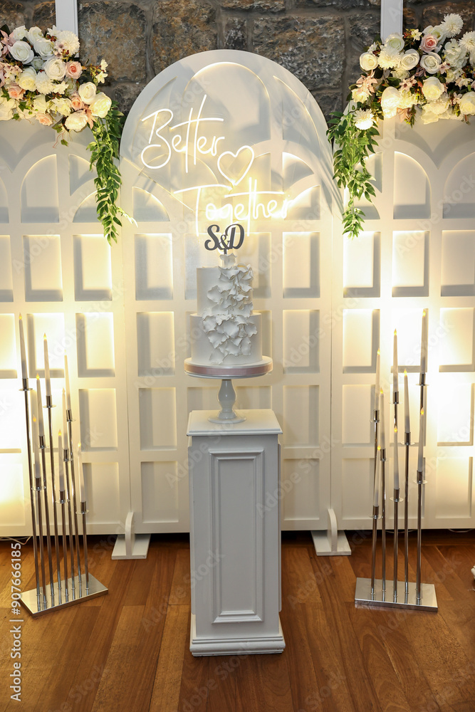 Refined Wedding Cake Presentation with Flowers and Lighting Inside Venue