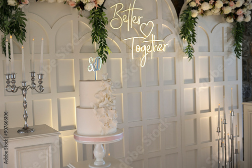 Refined Wedding Cake Presentation with Flowers and Lighting Inside Venue