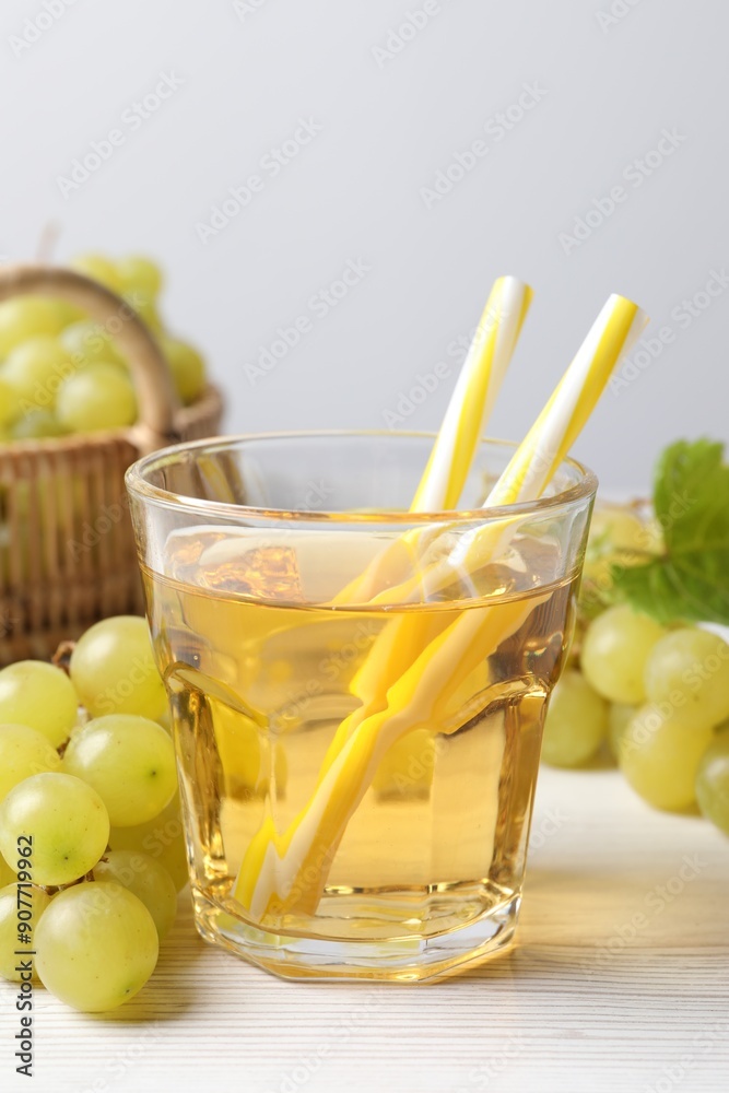 Ripe grapes and glass of tasty juice on white wooden table Ripe grapes and glass of tasty juice on white wooden table